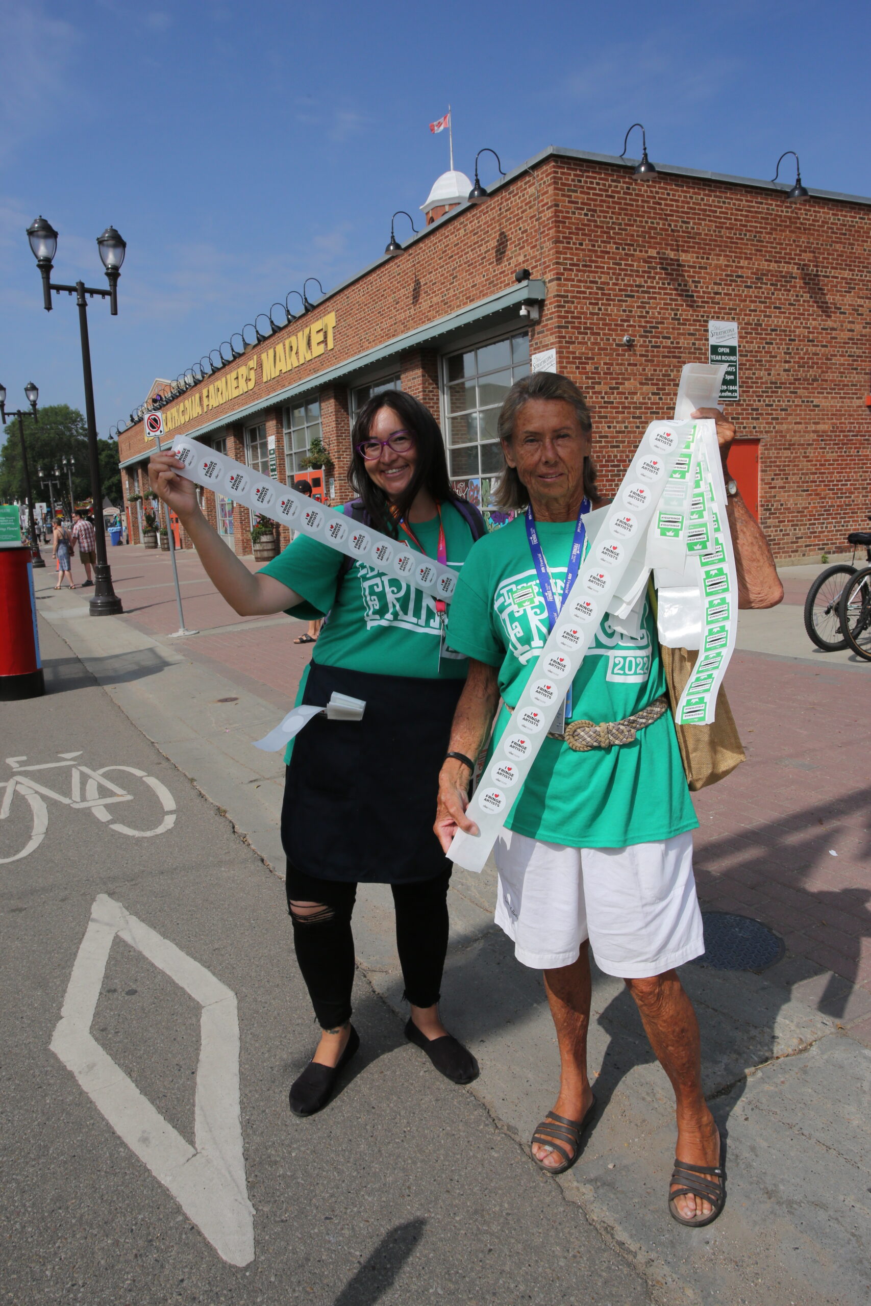 Two volunteers standing outside with the longest reels of stickers.