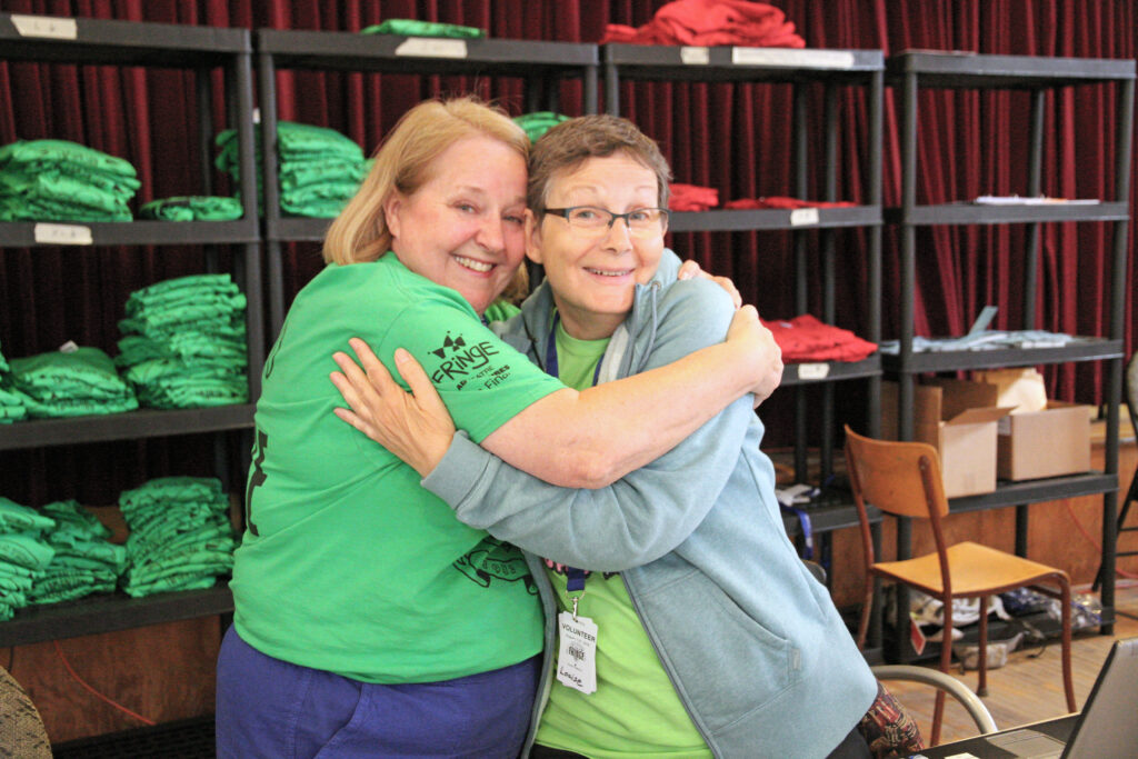 Two Female Volunteers are smiling and hugging each other.