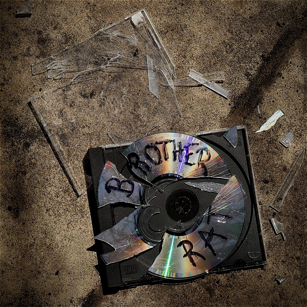 A CD and its case is shattered on the ground. "Brother Rat" is written in Sharpie on the broken disc.