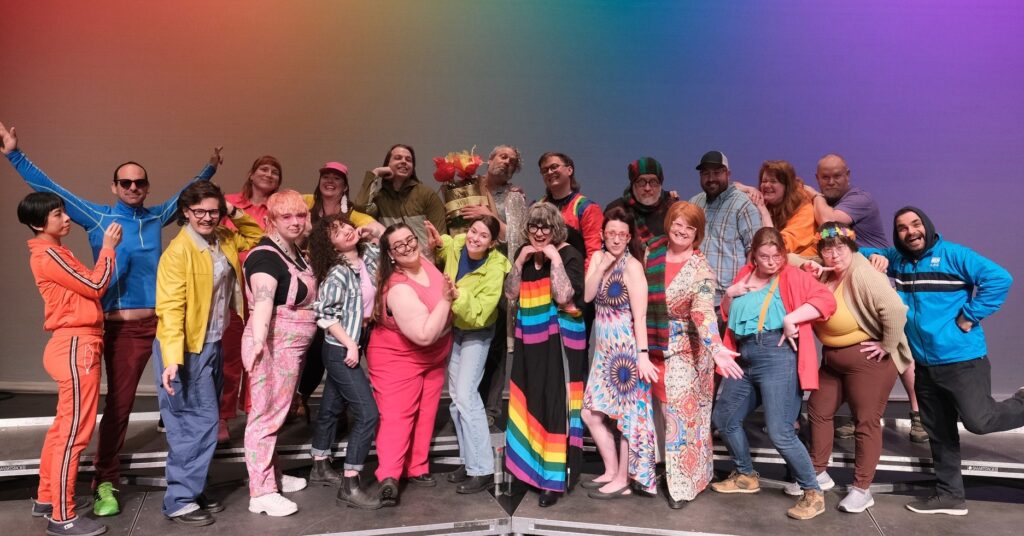 The Fringe Theatre Staff wearing colourful outfits in front of an array of colours.