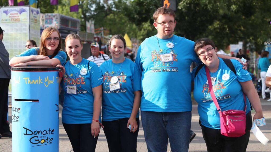 A group of Volunteer in blue shirts gathered an smiling.