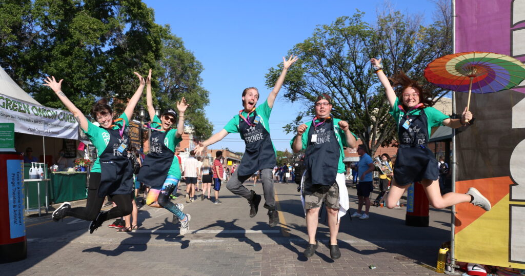 Volunteers wearing black aprons and jumping in the air.