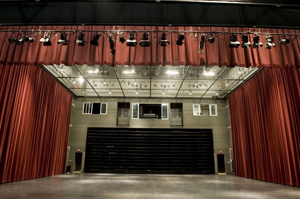 The Westbury Theatre with large red curtains, empty of all seats.